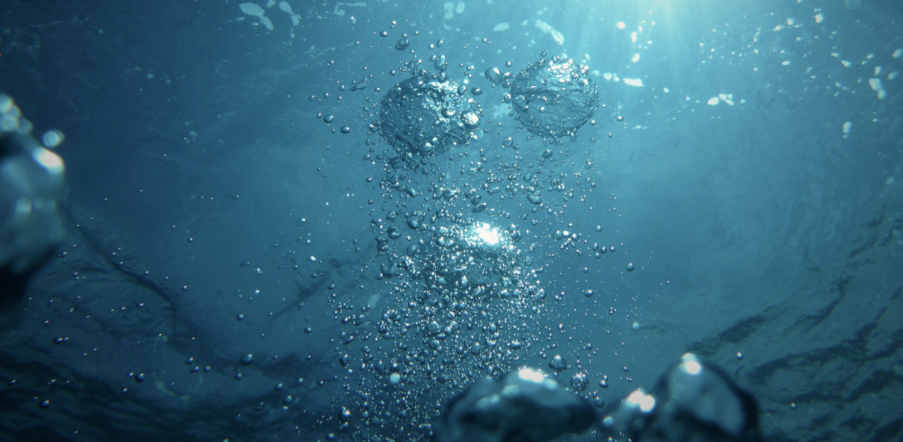 Underwater photograph of bubbles, with light shining downa nd through the air bubbles from above
